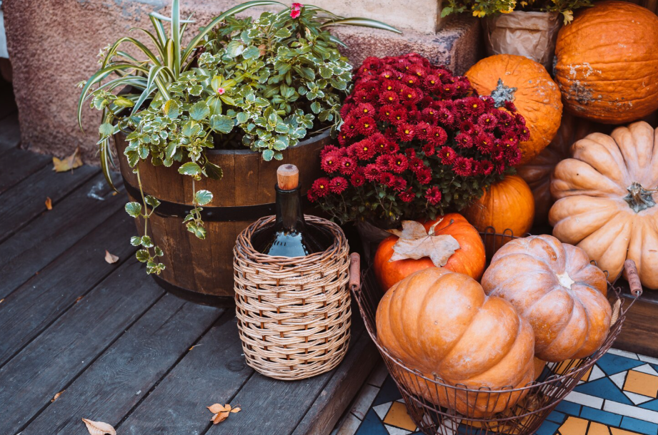 Budget-friendly fall porch swaps with pumpkins, mums, and greenery arranged on a cozy wooden porch.