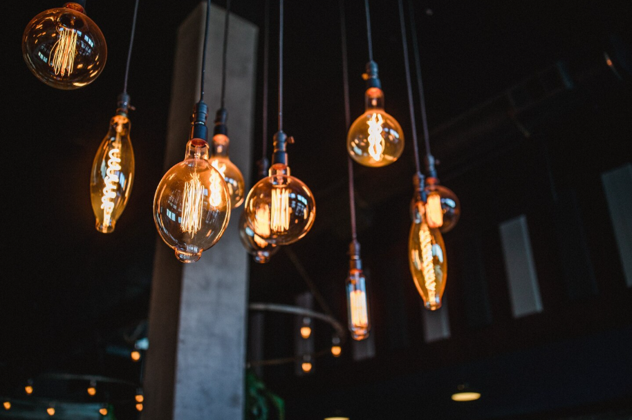 Modern statement lighting ideas with hanging Edison bulb pendants in a dark interior.