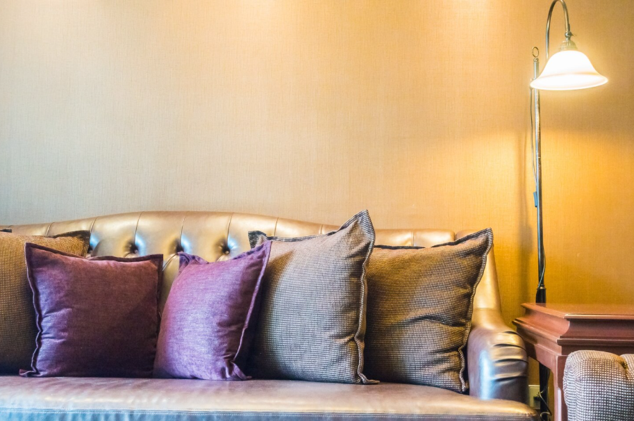 Brown leather sofa with luxe throw pillows and warm lighting creating an elegant living room design upgrade.