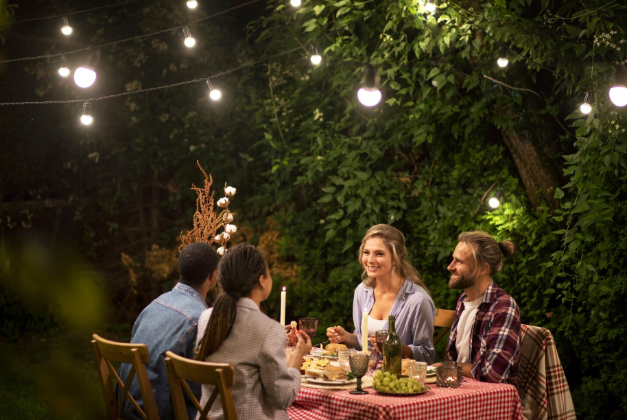 Friends enjoying al fresco dining at a cozy outdoor table under string lights