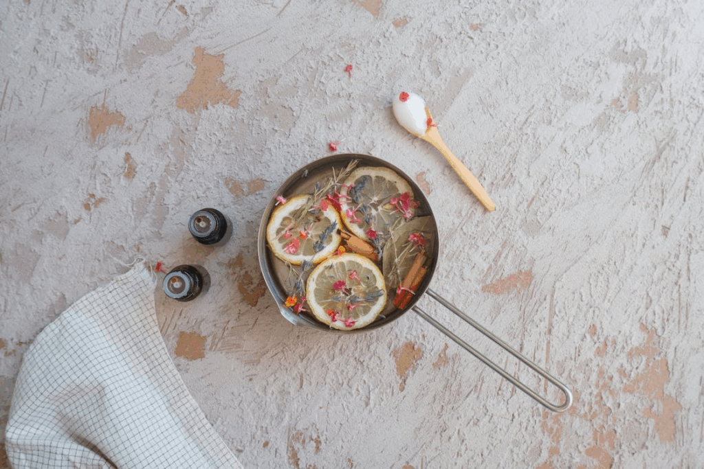 DIY simmer pot with lemon slices, cinnamon sticks, and herbs for signature home scent ideas.