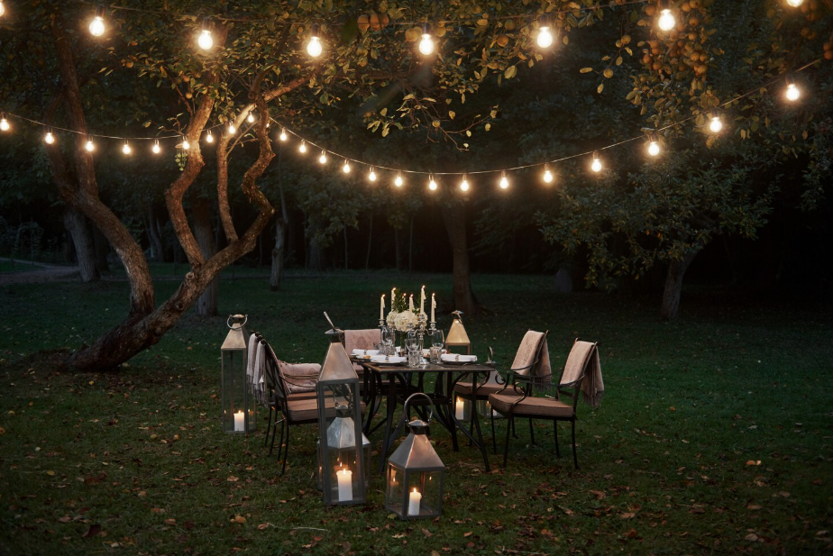 Outdoor lighting ideas with string lights and lanterns for a cozy atmosphere in a garden.