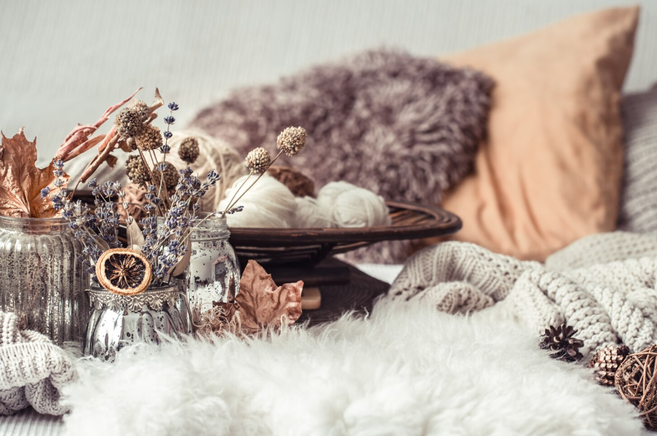 Cozy seasonal décor with knit blankets, fluffy pillows, and dried autumn flowers for an elegant summer to fall decorating transition.