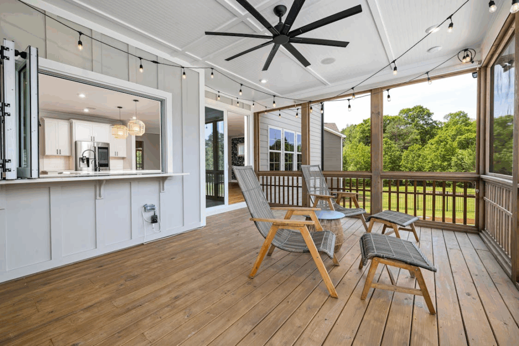 Screened-in porch with a crisp white painted ceiling, modern ceiling fan, and wooden deck