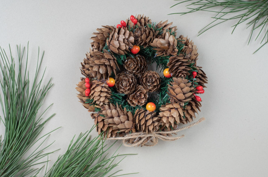 Natural pinecone wreath with green sprigs, berries, and jute bow