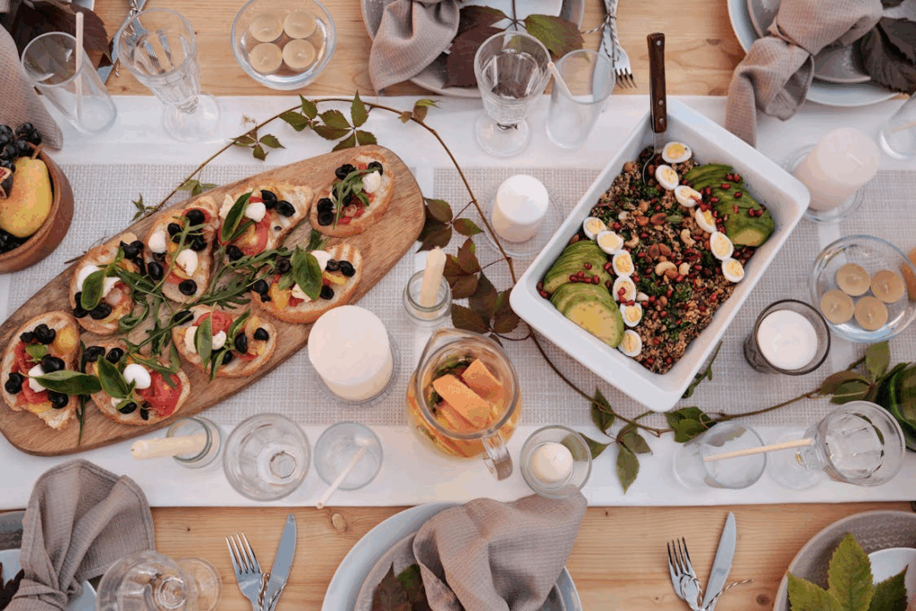 Rustic outdoor dining table with fresh bruschetta, quinoa salad, and herbs for a garden-to-table dinner party.