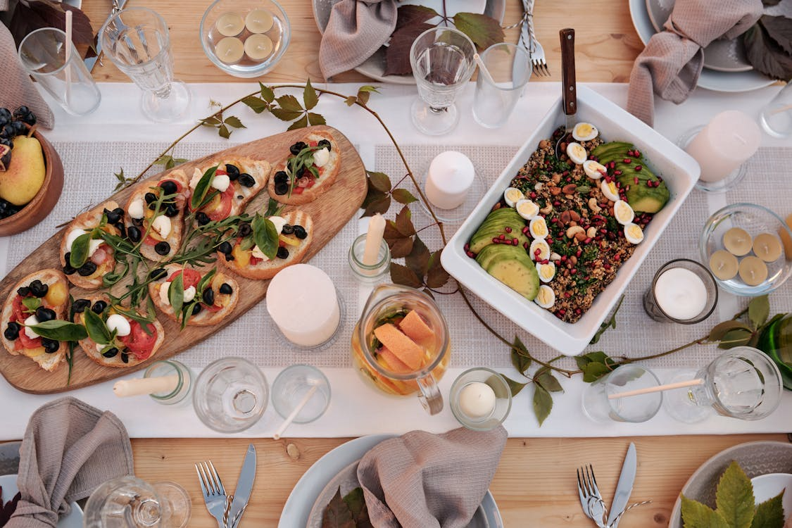 Rustic outdoor dining table with fresh bruschetta, quinoa salad, and herbs for a garden-to-table dinner party.