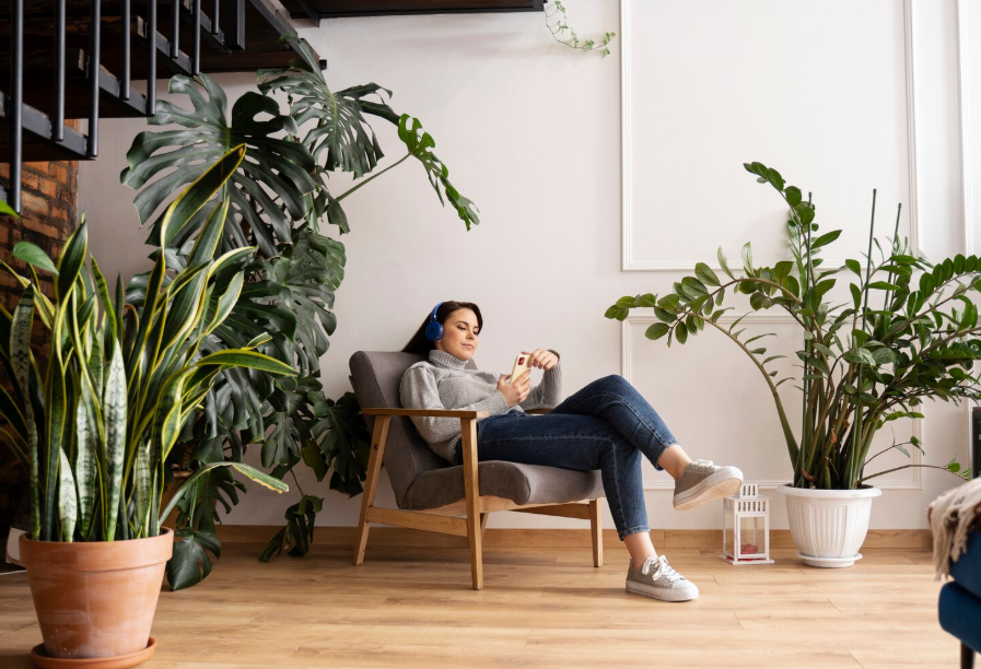Woman relaxing in a modern living room decorated with large indoor plants and natural wood accents.